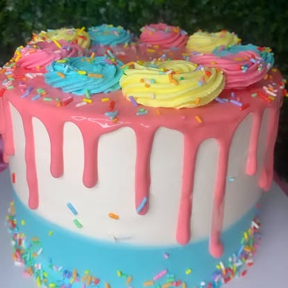 Bolo azul com cobertura rosa e confeitos